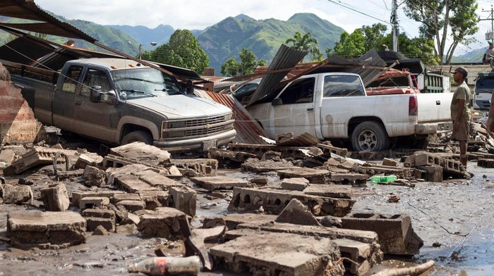A man walks near damaged vehicles after devastating floods swept through the town after Hurricane Beryl passed off the Venezuelan coast, in Cumanacoa, Venezuela, July 2, 2024. REUTERS/Samir Aponte      TPX IMAGES OF THE DAY