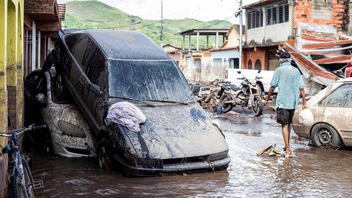 A man walks near damaged vehicles after devastating floods swept through the town after Hurricane Beryl passed off the Venezuelan coast, in Cumanacoa, Venezuela, July 2, 2024. REUTERS/Samir Aponte      TPX IMAGES OF THE DAY