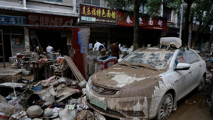 A resident holds a child as she sits at a shop after a flood following heavy rainfall in Pingjiang county of Yueyang, Hunan province, China July 3, 2024. REUTERS/Tingshu Wang     TPX IMAGES OF THE DAY