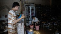 Warga membersihkan rumahnya usai banjir reda.