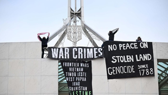 Spanduk Dukung Palestina Membentang di Gedung Parlemen Australia An Australian Federal Police officer removes a Pro-Palestinian protest banner as it hangs in the forecourt of the Australian Parliament House, in Canberra, Australia, July 4, 2024. REUTERS/Tracey Nearmy