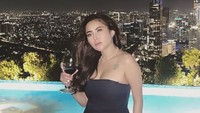 Pakaian serba hitam yang elegan dipilihnya untuk hangout ke sebuah lounge. Segala wine dipegangnya saat berfoto di pinggir kolam. Foto: Instagram/ayuaulia