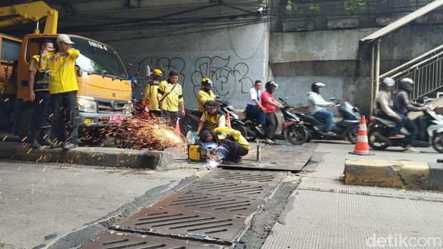 Petugas Bina Marga memperbaiki penutup gorong-gorong underpass Manggarai yang macet.