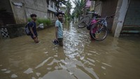 Sejumlah warga melintas di jalanan yang terendam banjir setinggi lutut.