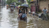 Penarik becak mengangkut penumpang melalui jalan yang banjir di Guwahati, India, Jumat (5/7/2024).