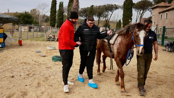 Matteo Santopadre, a former shooting champion who remained in a coma for months after a car accident, attends a hippotherapy session to regain his mobility at San Giovanni Battista Hospital, with his physiotherapist Antonio Spinelli and a horse groom in Rome, Italy February 9, 2024. REUTERS/Yara Nardi