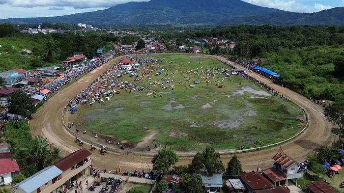 Foto udara sejumlah joki memacu kudanya pada kelas CD 2 tahun pemula Divisi III jarak 1.200 meter dalam ajang Pacu Kuda Wali Kota Cup dengan latar Gunung Singgalang di Gelanggang Bukit Ambacang Bukittinggi, Sumatera Barat, Sabtu (6/7/2024). Kejuaraan pacuan kuda tersebut diikuti puluhan ekor kuda dengan 12 pertandingan, dua di antaranya kelas bogie tradisional. ANTARA FOTO/Iggoy el Fitra/foc.