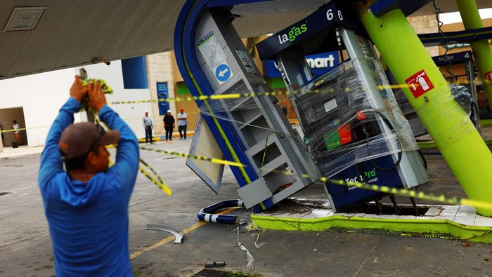 A person holds caution tape at a gas station that was hit by Hurricane Beryl, which has now downgraded to tropical storm, in Puerto Aventuras, Mexico, July 5, 2024. REUTERS/Jose Luis Gonzalez