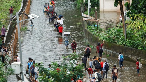 People walk on a waterlogged street after heavy rains in Mumbai, India, July 8, 2024. REUTERS/Francis Mascarenhas