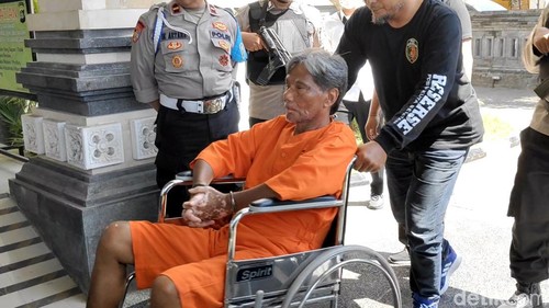 Purwadi duduk di kursi roda setelah betisnya luka akibat tembakan peluru polisi, Senin (8/7/2024). (Agus Eka/detikBali)