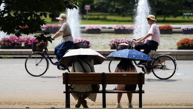 Orang-orang yang memegang payung duduk di bangku di bawah terik matahari di sebuah taman di Tokyo, Senin, 8 Juli 2024. Cuaca panas pada hari Senin telah terjadi dengan suhu meningkat lebih dari 35 derajat Celcius (95 derajat Fahrenheit) di Tokyo, menurut Jepang Badan Meteorologi. (AP Photo/Eugene Hoshiko)