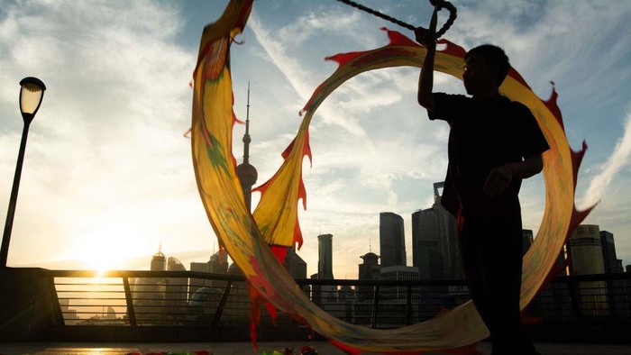 A woman is exercising the dragon dance during the early morning sunrise along the Bund in Shanghai, China, on July 8, 2024. (Photo by Ying Tang/NurPhoto via Getty Images)