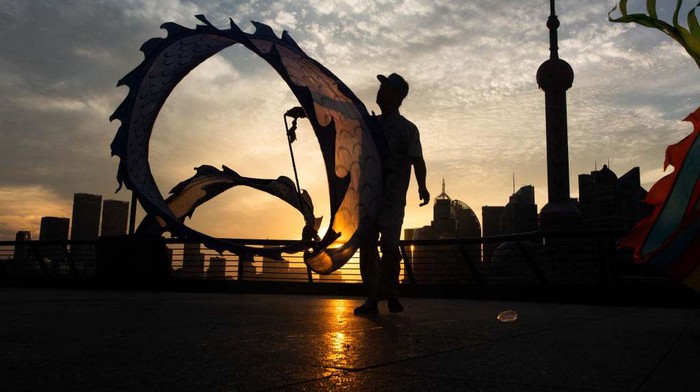 A woman is exercising the dragon dance during the early morning sunrise along the Bund in Shanghai, China, on July 8, 2024. (Photo by Ying Tang/NurPhoto via Getty Images)