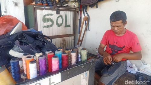 Dairuh Salam (42) tengah memperbaiki sepatu siswa saat ditemui di tempat usahanya, Jalan Gatot Subroto (Gatsu) Timur Nomor 16 Denpasar, Selasa (9/7/2024). (Ni Made Lastri Karsiani Putri/detikBali)