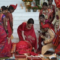 Salah satu peserta nikah massal berlutut di hadapan Nita Ambani sebagai bentuk ungkapan terima kasih. Nita juga berbalut saree merah, tapi gayanya maksimal dipadu perhiasan mewah. (Foto: AP Photo/Rafiq Maqbool)