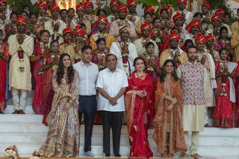 Chairman of Reliance Industries Limited Mukesh Ambani, third from left, poses for a photograph with his family members and underprivileged couples during a mass wedding organized by him as the part of pre-wedding celebrations of his youngest son, Anant Ambani, in Navi Mumbai, India, Tuesday, July 2, 2024. (AP Photo/Rafiq Maqbool)