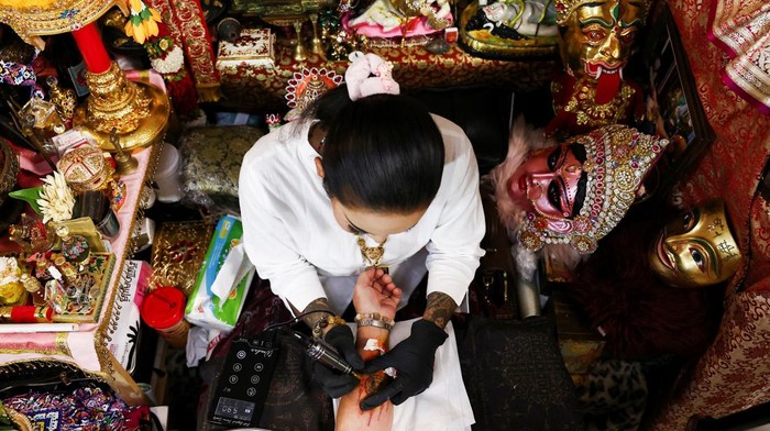 Tattoo master Am Sriphromyan works on a magic tattoo on the forearm of 56-year-old Kamonwan Patimahongthong, of the pattern of the famous Pop Mart's Labubu monster, which is believed to have mystical power and bring good fortune, in Nonthaburi province on the outskirts of Bangkok, Thailand, June 12, 2024. REUTERS/Chalinee Thirasupa
