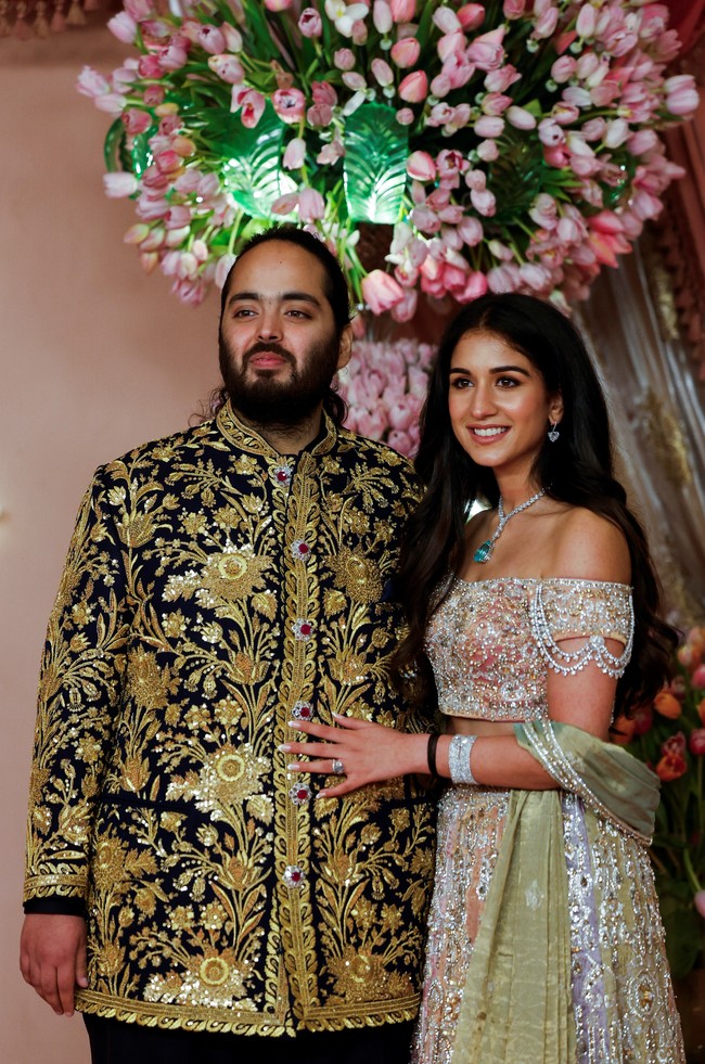 Tidak kalah menarik, calon istrinya, Radhika Merchant, juga mengenakan busana dari Abu Jani Sandeep Khosla. Dia tampil menawan dengan lehenga (sari) berpanel yang terinspirasi dari lampu gantung. Busana tersebut dihiasi kristal Swarovski, dan blouse off-shoulder dengan dupatta (selendang) hijau pistachio yang disampirkan di lengannya. Foto: dok. Getty Images