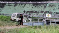 Pesepeda melihat sirkuit yang dipenuhi rumput liar di Velodrome, Malang, Jawa Timur, Rabu (10/7/2024).