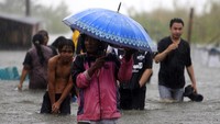 Sejumlah warga melintasi genangan air untuk mengungsi ke tempat yang lebih tinggi di Desa Hutadaa, Kecamatan Telaga jaya, Kabupaten Gorontalo, Gorontalo, Rabu (10/7/2024).