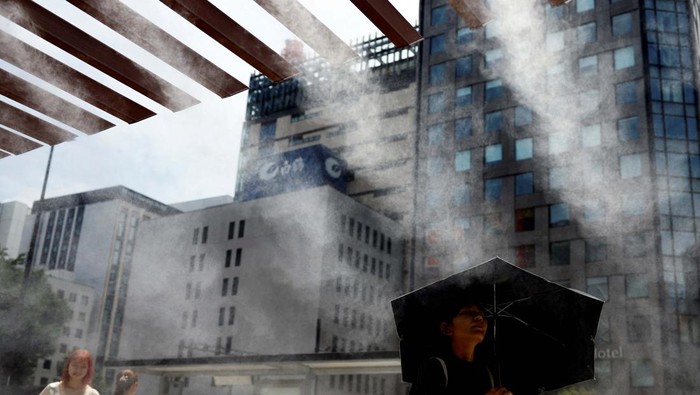 Passersby take a break under a cooling mist as the Japanese government issued a heatstroke alert in Tokyo and other prefectures, in Tokyo, Japan July 9, 2024. REUTERS/Issei Kato