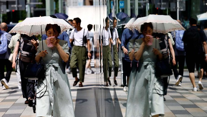 Passersby take a break under a cooling mist as the Japanese government issued a heatstroke alert in Tokyo and other prefectures, in Tokyo, Japan July 9, 2024. REUTERS/Issei Kato