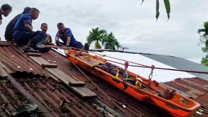 Petugas damkar evakuasi warga stroke di atap rumah.