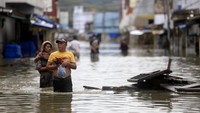 Sejumlah warga melewati jalan yang tergenang banjir di Kota Gorontalo, Gorontalo, Kamis (11/7/2024).