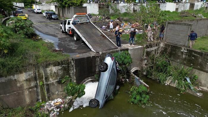 Sebuah mobil nyemplung ke saluran pembuangan limbah di Veracruz, Mexico, Rabu (10/7/2024). Hujan deras menjadi penyebab kecelakaan tersebut.