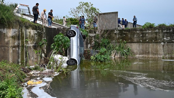 Sebuah mobil nyemplung ke saluran pembuangan limbah di Veracruz, Mexico, Rabu (10/7/2024). Hujan deras menjadi penyebab kecelakaan tersebut.