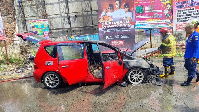 Mobil jenis Nissan Livina terbakar di bawah Fly Over Palur, Kecamatan Jaten, Kabupaten Karanganyar, Kamis (11/7/2024).