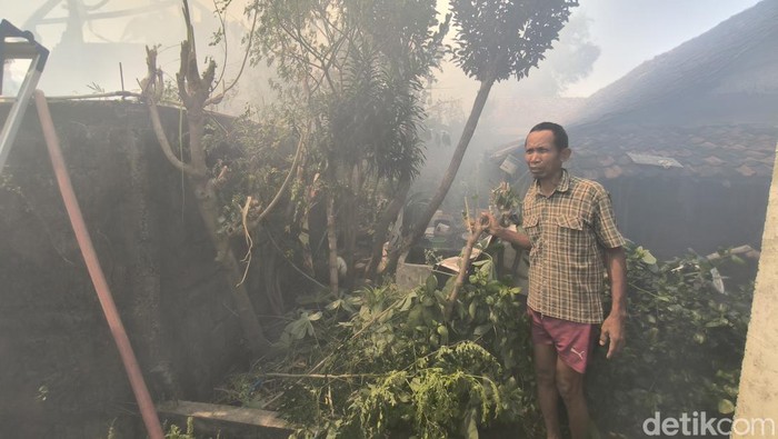 Nur Kholis saat menunjukan belakang rumahnya yang nyaris terbakar buntut kebakaran pabrik spons Gresik
