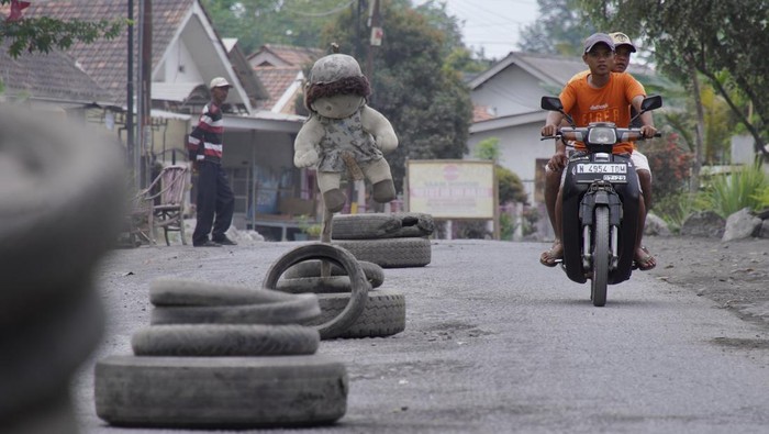Warga melintasi jalan rusak yang ditanami pohon pisang di Desa Condro, Kecamatan Pasirian, Lumajang, Jawa Timur, Kamis (11/7/2024). Aksi blokade jalan sejauh 1,2 kilometer menggunakan pohon pisang, mobil pikap, dan ban bekas tersebut sebagai bentuk protes warga akibat jalan rusak yang tak kunjung diperbaiki selama setahun terakhir. ANTARA FOTO/Irfan Sumanjaya/nym.
