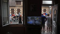 Warga menyaksikan dari pintu rumah mereka saat rombongan bersama pebalap Slovenia Tadej Pogacar, mengenakan seragam kuning pemimpin umum (kanan), melewati desa Ligny-le-Ribault pada etape kesepuluh Tour de France perlombaan bersepeda sejauh 187,3 kilometer (116,4 mil) dengan start di Orleans dan finis di Saint-Amand-Montrond, Prancis. AP/Daniel Cole