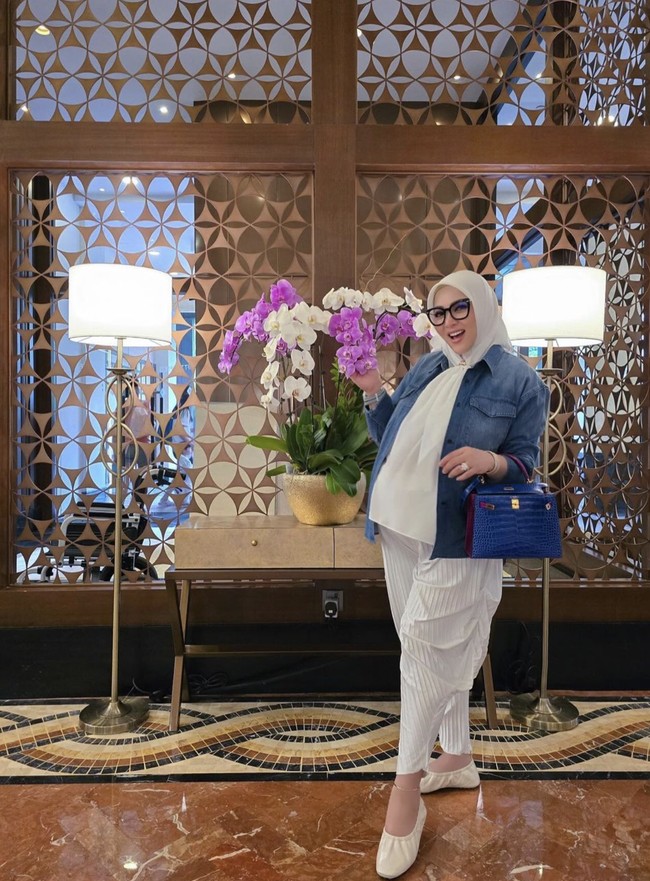 Meski perutnya sudah membesar, Syahrini tampak senang mengenakan setelan celana panjang. Kali ini ia memakai setelan putih-putih dengan celana pleats yang longgar. Foto: Instagram @princessyahrini