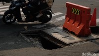 Jalan yang berlubang tersebut ditutup oleh barrier.