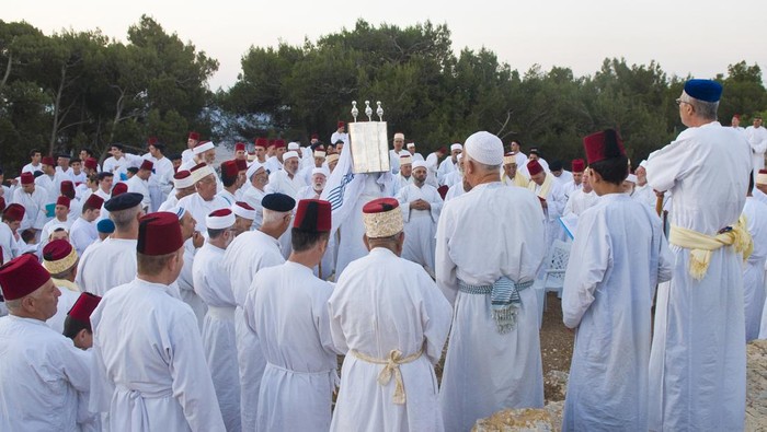 Nablus , West bank - June 24, 2012 : A priest of the ancient Samaritan community holds up a Torah scroll during the holy day of Shavuot in Mount Gerizim