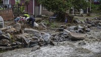 Warga mengumpulkan puing-puing di sekitar bangunan rumah di Plainfield, Vermont, Kamis (11/7/2024).