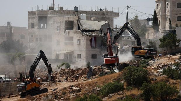 Warga Palesntina menyaksikan penghancuran rumah mereka yang dilakukan oleh militer Israel di Tepi Barat, Kamis (11/7/2024). (REUTERS/Mussa Qawasma)