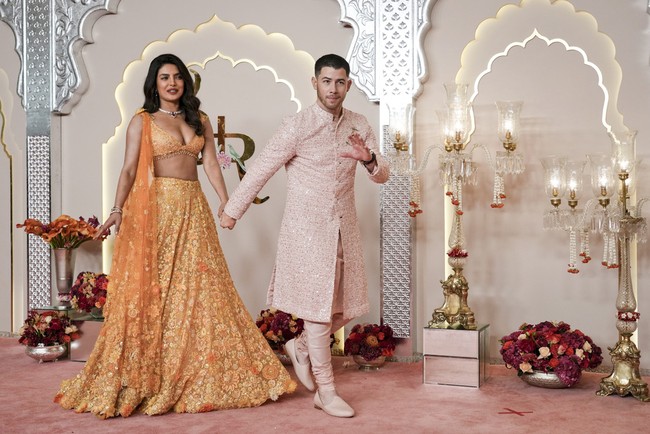 Acara yang digelar super-mewah ini mengundang sejumlah selebriti ternama dari Bollywood hingga mancanegara. Salah satunya Priyanka Chopra yang datang bersama suaminya Nick Jonas. Priyanka tampil cantik mengenakan lehenga warna oranye berbahan lace dan dihiasi bordir. Sementara Nick mengenakan tunik dan celana panjang berbahan tweed dalam warna pink pastel. Foto: AP/Rajanish Kakade