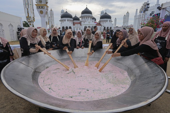Sejumlah warga Banda Aceh mengaduk bubur asyura saat pencatatan rekor Museum Rekor Dunia Indonesia (MURI) belanga terbesar dalam Sambot Muharram Raya di Masjid Raya Baiturrahman, Banda Aceh, Aceh, Sabtu (13/7/2024). Pencatatan rekor MURI memasak bubur asyura dengan belanga terbesar ukuran 2,6 meter x 2,6 meter tersebut merupakan rangkaian kegiatan Sambot Muharram Raya yang digelar Bank Indonesia Aceh dengan melibatkan masyarakat, sebagai upaya melestarikan tradisi yang dilakukan setiap menyambut bulan Muharram. ANTARA FOTO/Khalis Surry/Spt.