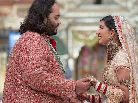 Dalam foto yang disediakan oleh Reliance Industries, Anant Ambani, kiri, putra miliarder Mukesh Ambani, berpegangan tangan dengan Radhika Merchant saat upacara pernikahan mereka di Jio World Convention Center di Mumbai, India, Jumat, 12 Juli 2024. (Reliance Industries via AP)