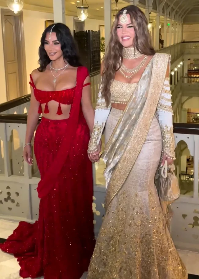 Kim Kardashian dan Khloe Kardashian tampil seksi dengan busana lehenga yang telah dimodifikasi jadi lebih kekinian. Namun penampilan Kim menuai kritik, ia dianggap melanggar tradisi di India karena memakai busana merah. Dalam upacara pernikahan Hindu modern, warna merah secara tradisional hanya dipakai oleh pengantin wanita. Foto: Dok. Instagram Kim Kardashian