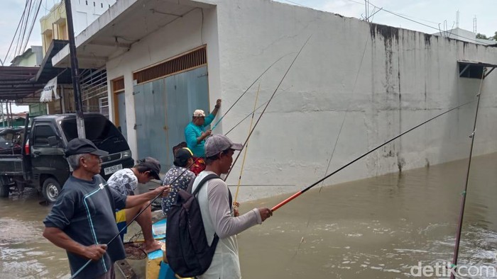Pengungsi banjir di Kota Gorontalo, Provinsi Gorontalo, mengisi waktu dengan memancing ikan di saluran air atau drainase.