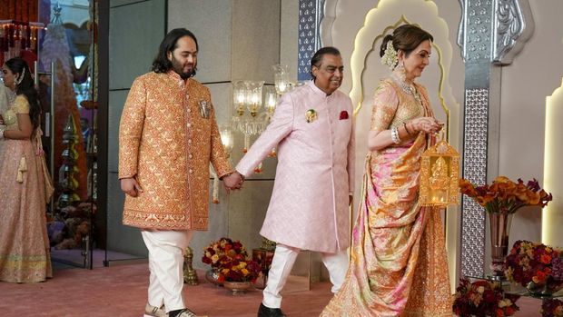Miliarder Mukesh Ambani, tengah, menggandeng tangan putranya Anant Ambani saat mereka berjalan bersama Nita Ambani, kanan, di pernikahan Anant dan Radhika Merchant di Jio World Convention Center di Mumbai, India, Jumat, 12 Juli 2024. (AP Photo /Rajanish Kakade)