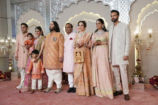 Anant Ambani memasangkan Sherwani, mantel lengan panjang khas India warna emas-merah, dengan celana ivory. Pria berusia 29 tahun ini menyempatkan pose bersama keluarganya sebelum melangsungkan upacara pernikahan di Jio World Center, Mumbai, India.  Foto: AP/Rajanish Kakade