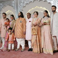 Anant Ambani memasangkan Sherwani, mantel lengan panjang khas India warna emas-merah, dengan celana ivory. Pria berusia 29 tahun ini menyempatkan pose bersama keluarganya sebelum melangsungkan upacara pernikahan di Jio World Center, Mumbai, India.  Foto: AP/Rajanish Kakade