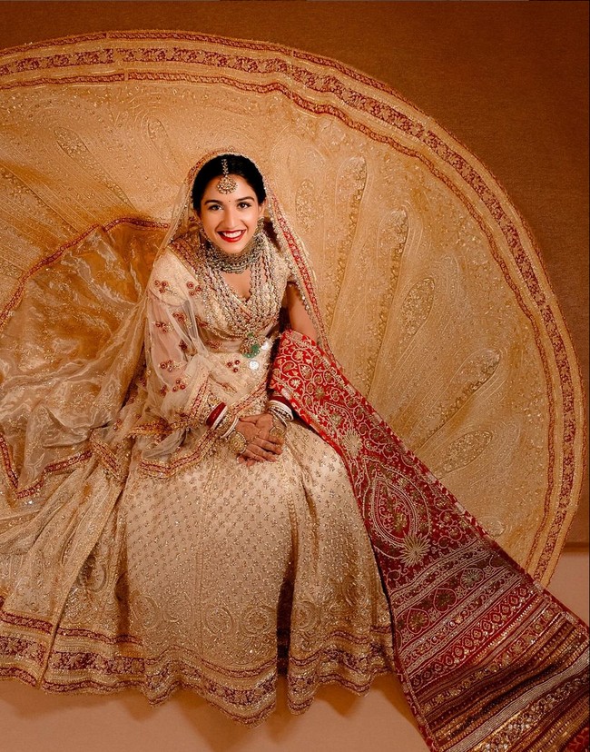 Radhika mengenakan mengenakan baju pengantin karya Abu Jani Sandeep Khosla. Pemilihan warna merah dan putih sendiri melambangkan tradisi Gujarati. Gayanya dipercantik dengan berbagai aksesori mewah milik nenek, ibu, dan saudari. Foto: Instagram/@rheakapoor @@signe_vilstrup @@luismonteirophotography