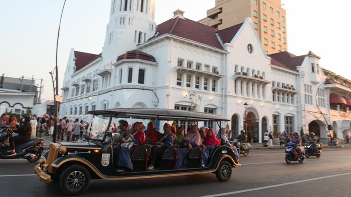 Wisatawan menggunakan jasa mobil listrik wisata Toer Wagen di Kota Lama Surabaya, Surabaya, Jawa Timur, Sabtu (13/7/2024). Mobil listrik wisata Toer Wagen yang dipatok dengan harga Rp20 ribu per wisatawan sekali jalan  itu berkeliling menyaksikan suasana kawasan wisata sejarah Kota Lama Surabaya dengan rute yang telah ditentukan. ANTARA FOTO/Didik Suhartono/Spt.