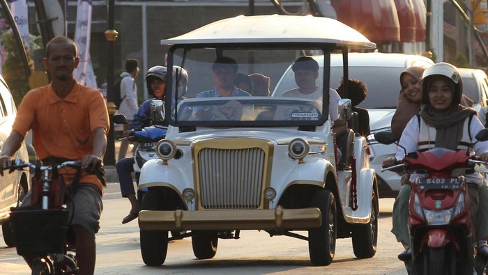 Wisatawan menggunakan jasa mobil listrik wisata Toer Wagen di Kota Lama Surabaya, Surabaya, Jawa Timur, Sabtu (13/7/2024). Mobil listrik wisata Toer Wagen yang dipatok dengan harga Rp20 ribu per wisatawan sekali jalan  itu berkeliling menyaksikan suasana kawasan wisata sejarah Kota Lama Surabaya dengan rute yang telah ditentukan. ANTARA FOTO/Didik Suhartono/Spt.